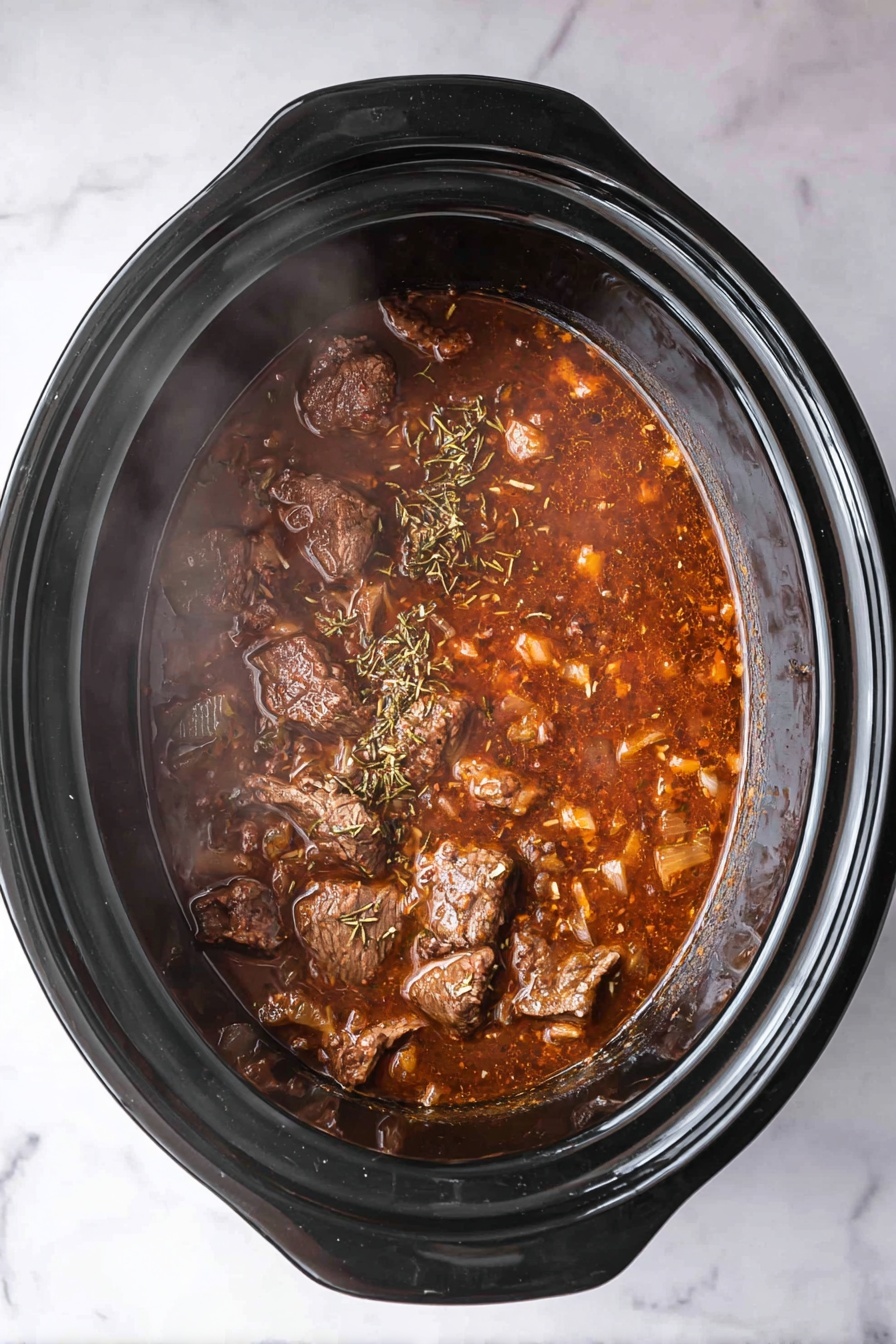 The image shows a top view of a black slow cooker filled with a rich brown stew. The stew has visible chunks of cooked meat scattered throughout, surrounded by a thick brown sauce with small pieces of soft, cooked onions and sprinkled with dried herbs. The stew looks hot with visible steam rising from the surface. The slow cooker sits on a white marbled surface photo taken with an iphone --ar 2:3 --v 7
