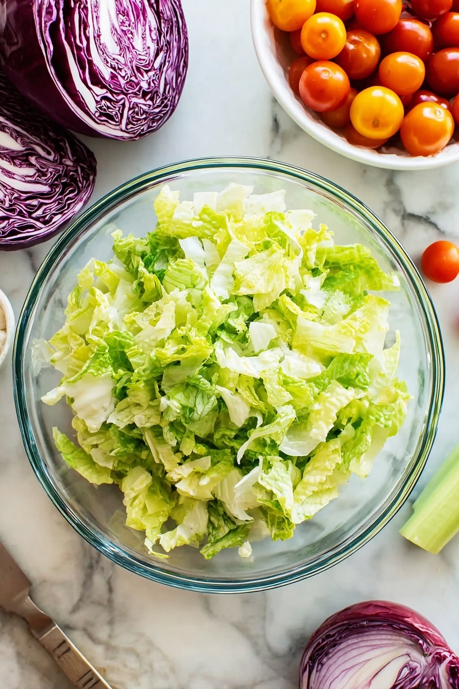 A clear glass bowl filled with a colorful salad showing multiple layers: bright green lettuce leaves form the base with crispy texture, scattered with deep purple radicchio strips adding contrast; small cherry tomatoes in orange-red halves are spread evenly throughout; cream-colored chickpeas and small pale yellow cheese cubes add round and block shapes; tiny bits of orange, white, and red pieces are mixed in, giving texture variety; two wooden salad spoons rest inside the bowl; the bowl sits on a white marbled surface. photo taken with an iphone --ar 2:3 --v 7